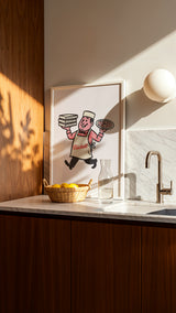 Kitchen counter with a framed illustration, basket of lemons, and sink.